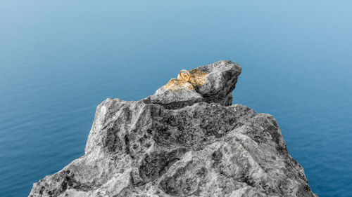 Rock formation in sea against blue sky