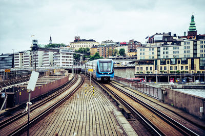 Train on railroad track in city against sky