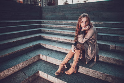 Full length of woman sitting on staircase