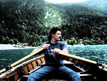 Young man sitting in boat on lake