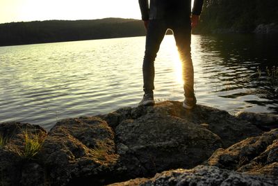 Low section of man standing on rock at beach