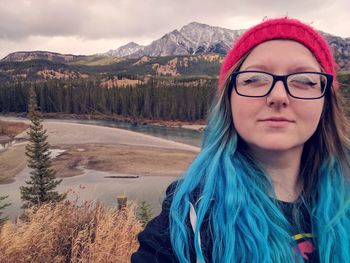 Portrait of woman with dyed hair against mountains