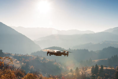 Small modern drone hovering taking picture of sunrise in mountai