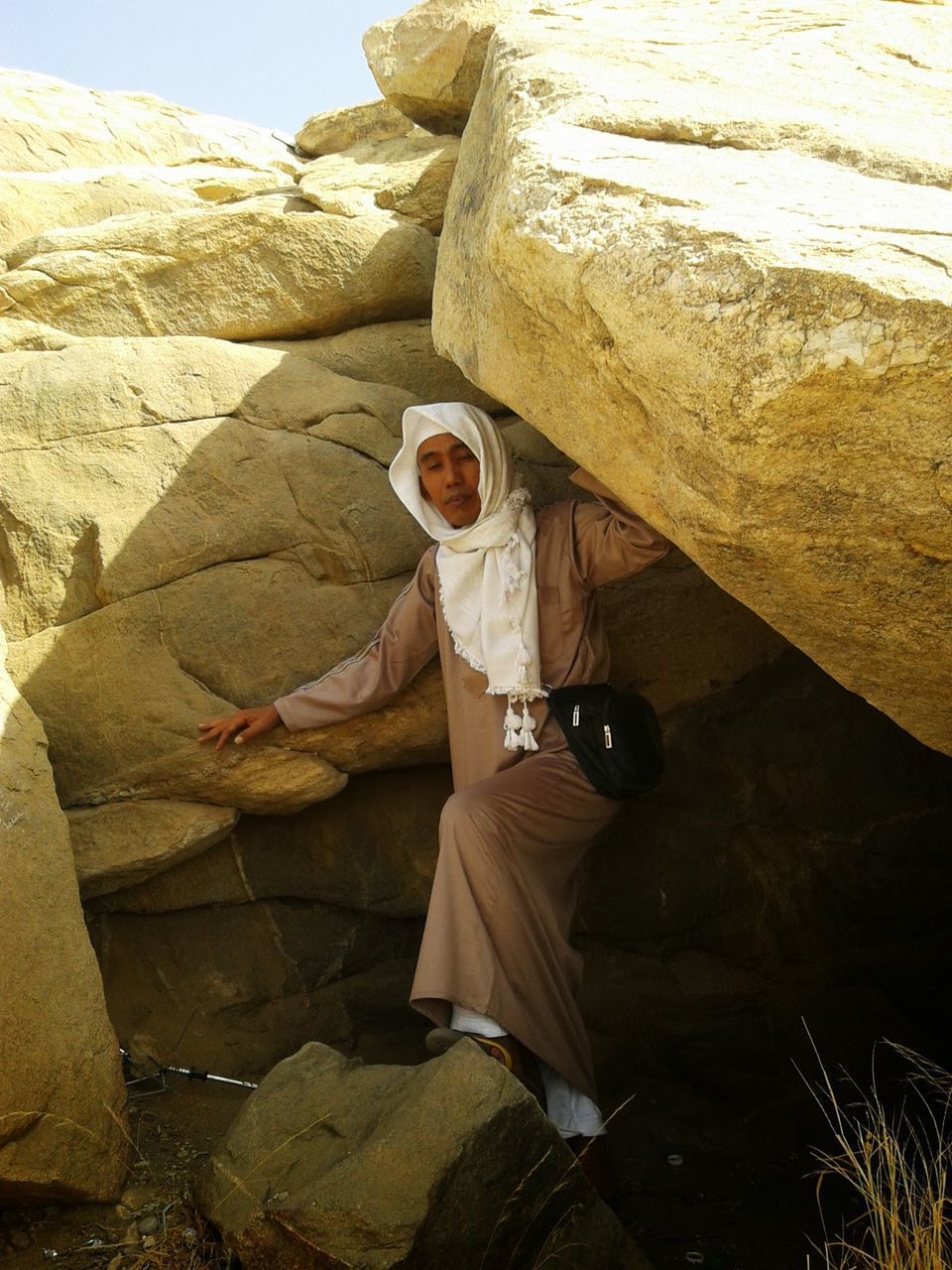 MIDSECTION OF WOMAN HOLDING ROCK ON ROCKS