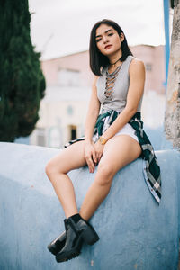 Portrait of a young latina woman sitting on a fence with a relaxed pose
