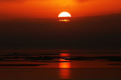 Scenic view of sea against dramatic sky at sunset