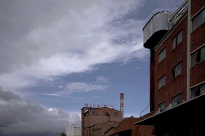 Low angle view of buildings against cloudy sky