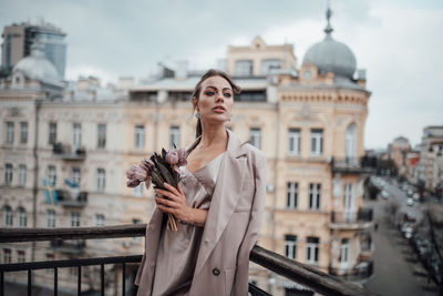 Full length of woman standing against buildings in city