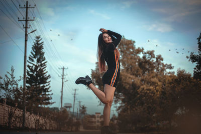 Low angle view of woman with arms raised against sky