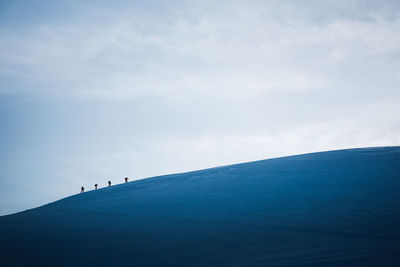 A group of skiers walks across a snowy ridge in iceland