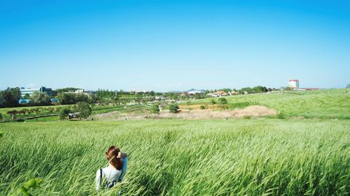 Rear view of woman on agricultural field against clear sky