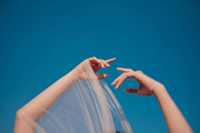 Low angle view of people hand against blue background