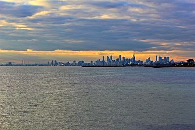 Cityscape against cloudy sky at sunset