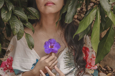 Close-up of woman holding leaves of flowering plant