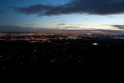 Illuminated cityscape against sky during sunset