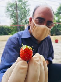 Close-up of man holding strawberry