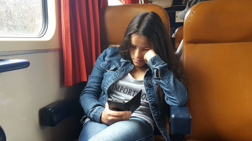 Girl using phone while sitting in train