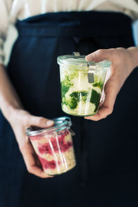 Midsection of woman holding food in glass containers