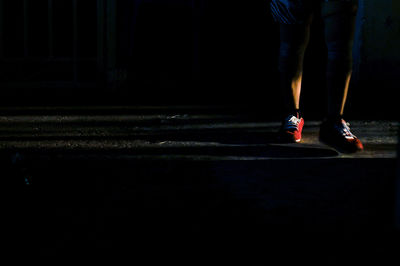 Low section of man standing on ground at night