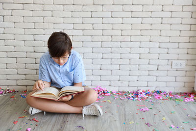 Girl sitting on book against wall