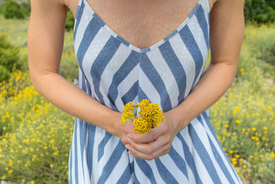 Midsection of woman holding yellow flowers