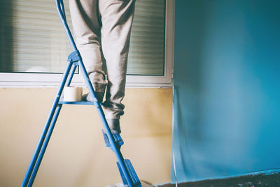 Low section of man standing in front of ladder