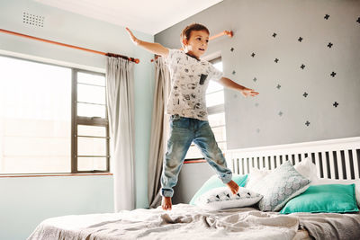 Boy jumping on bed at home