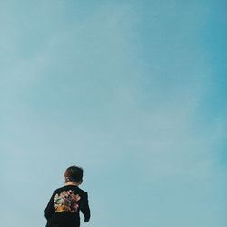 Rear view of boy against blue sky