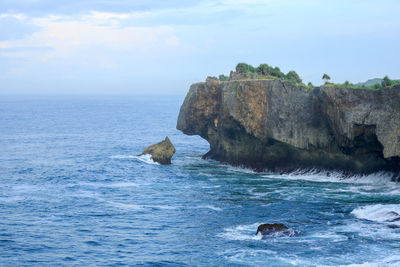 Rock formation in sea against sky