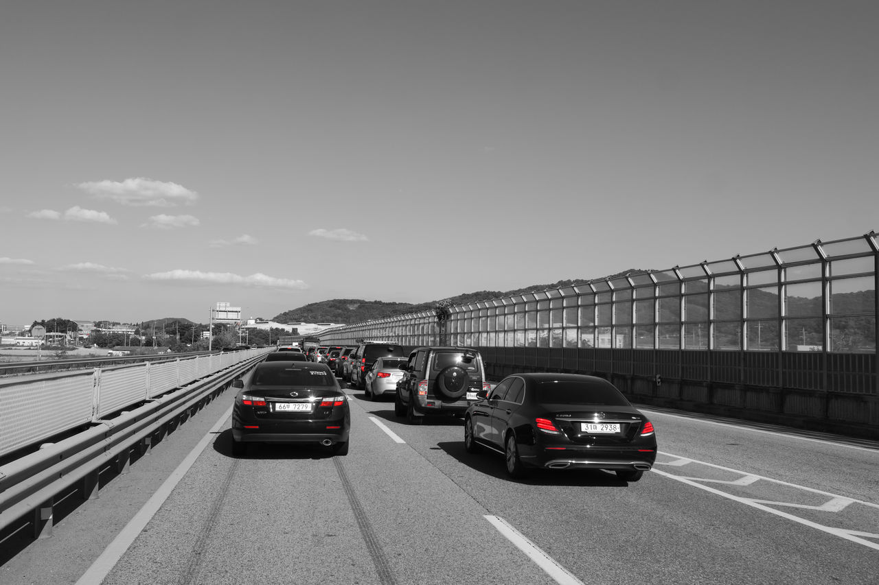 VEHICLES ON ROAD AGAINST SKY