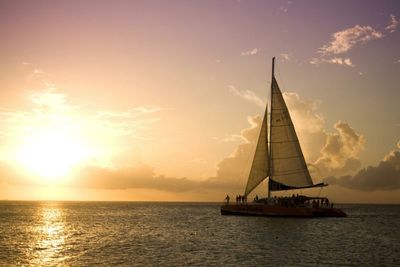 Boat sailing in sea against sky during sunset