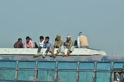 People on boat in sea against clear sky