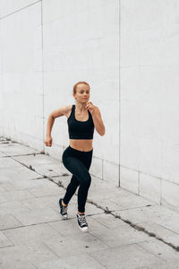 Full length of woman running against wall