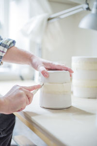 Cropped image of female potter cutting vase on workbench at store