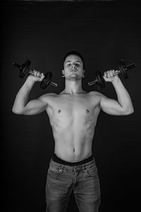 Portrait of young man holding camera over black background