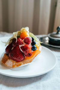 A colorful fruit dessert featuring strawberries, blueberries, and other fruits is presented.