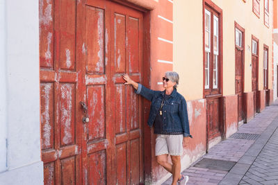 Smiling senior woman standing by door in city