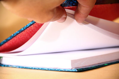 Close-up of hand holding book on table