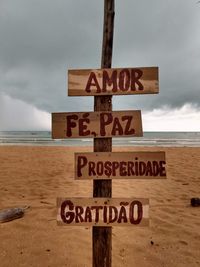 Information sign on beach against sky