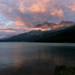 Scenic view of lake by mountains against sky during sunset