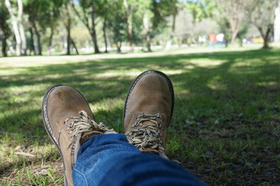 Low section of man wearing shoes resting on grassy field at park