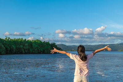 Rear view of woman standing by sea against sky