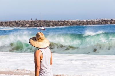 Side view of woman standing on beach against clear sky