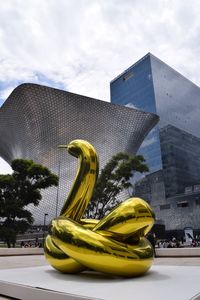 Yellow sculpture in city against sky