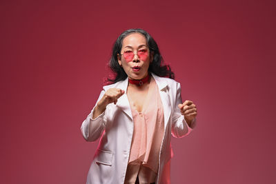 Portrait of young woman standing against yellow background