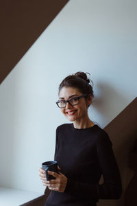 Young woman using mobile phone against wall