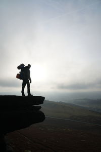 Side view of silhouette man standing on mountain against sky