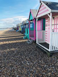 Multi colored huts at shore of beach against sky