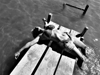 Woman lying on pier over sea