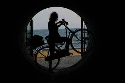 Silhouette man and woman standing on bicycle at night